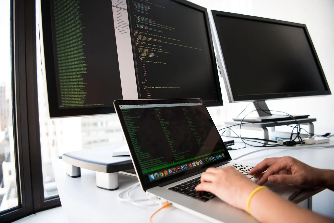 Website Design in Mysore — developer working with code on laptop and desktop screens